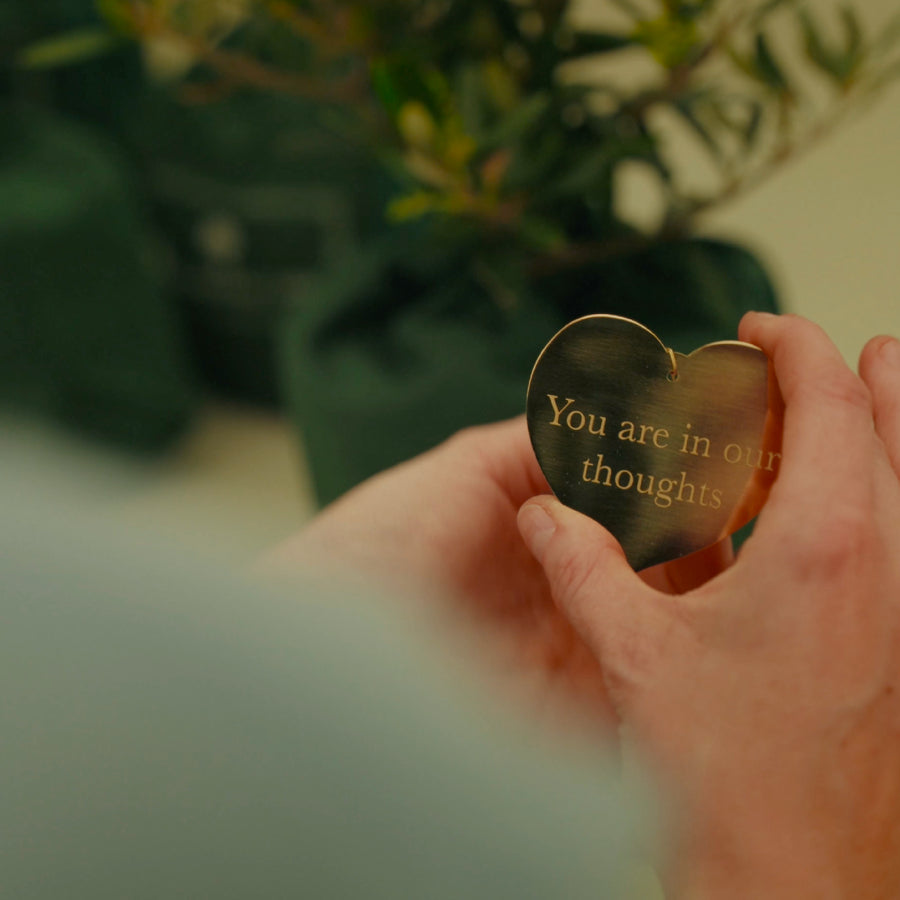 A close up of hands wrapping a plaque. Gold heart shaped plaque with an engraving.